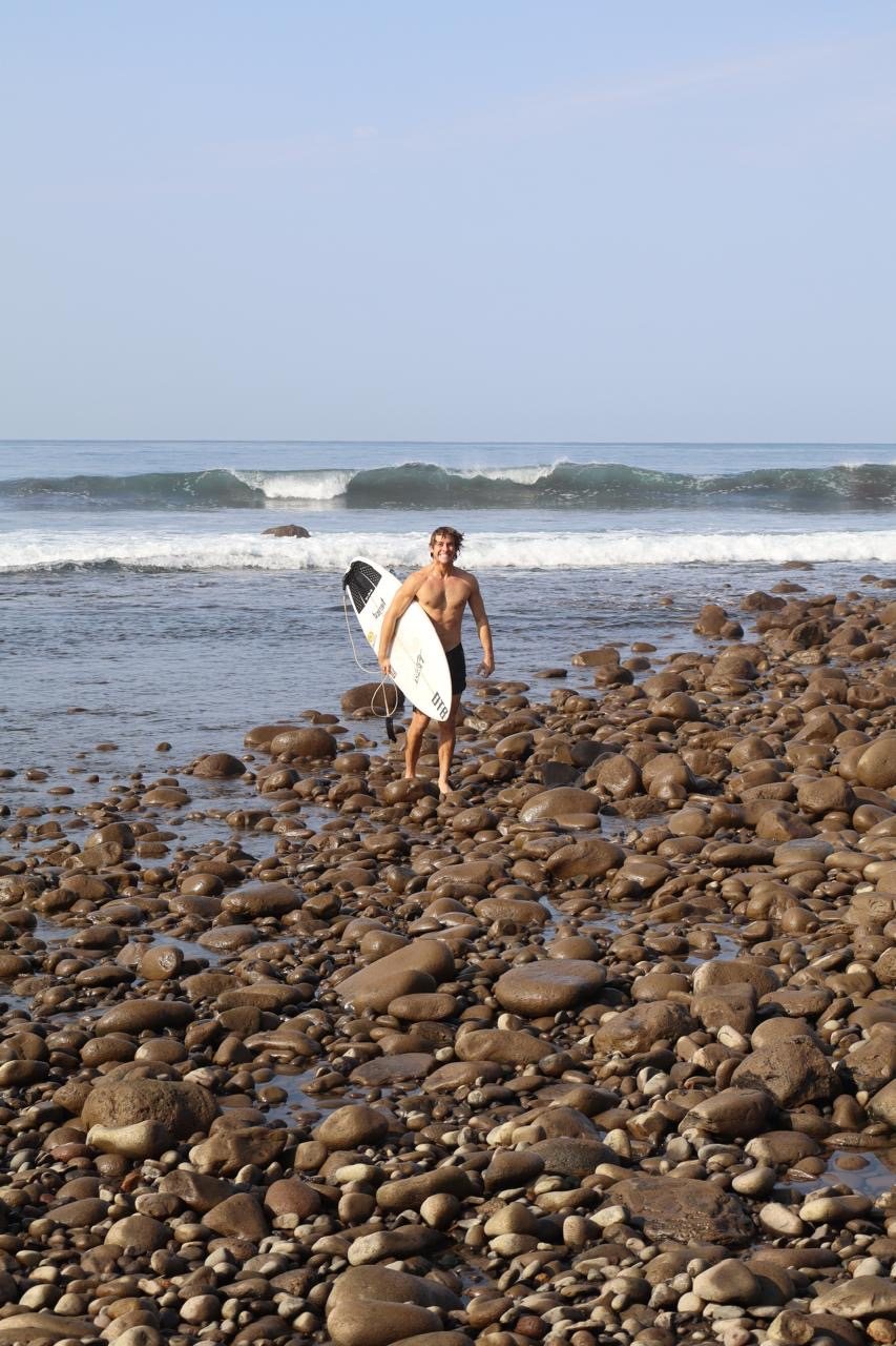 dalen on the beach with his surfboard